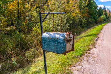 Old vintage roadside mailbox with key, in a rural area during the changing colors of autumn, fall foliage.