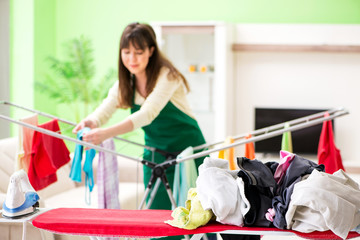 Young woman ironing clothing at home