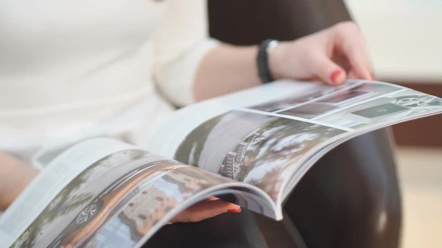 Close up. Beautiful girl reading women's magazine gloss