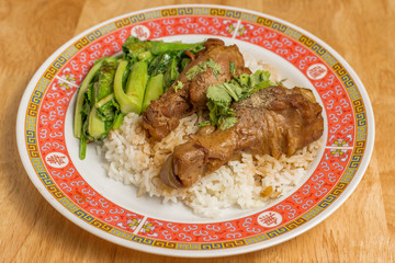 Stewed chicken or Braised chicken with Chinese kale and rice in dish on wooden table.