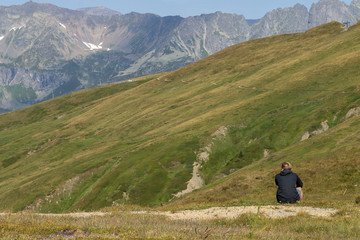 boy sitting in front of a mountain