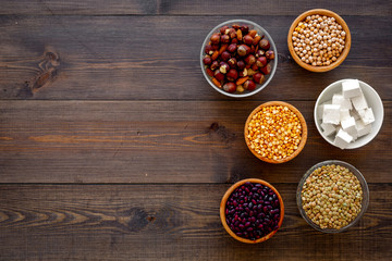 Vegan protein source. Legumes, nuts, cheese. Raw beans, chickpeas, lentil, almond, hazelnut on dark wooden background top view space for text