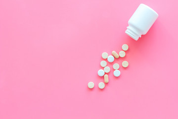 Medicine. Pills falling out of jar on pink background top view copy space