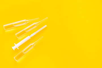 Flu vaccination concept. Syringe and ampoulie on yellow background top view copy space