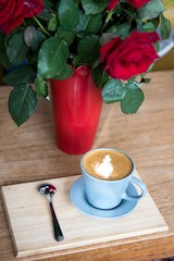 Coffee cup on tray with spoon and rose flowers