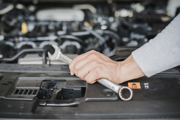 Hand of car mechanic with wrench at service center repair