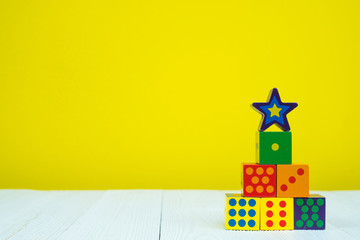 Square block puzzle toy on table with yellow background