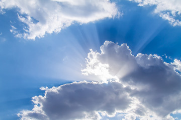 The rays of the sun from behind the white clouds