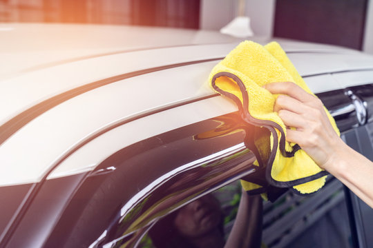 A Man Cleaning White Car With Yellow Microfiber Cloth.