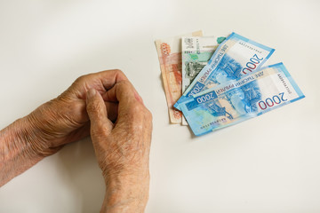 Hands of an old man with large denominations. Russia.