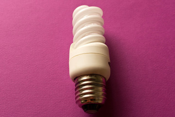 Energy saving light bulb on a purple background. The concept of energy saving