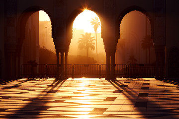 Great mosque of Hassan 2 at sunset in Casablanca, Morocco. Beautiful Arches of the Arab mosque in the sunset, sunlight rays - obrazy, fototapety, plakaty