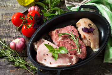 Fresh raw meat. Different types of raw pork meat, chicken fillet and beef with vegetables and herbs on wooden table.