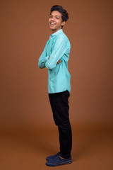 Fototapeta premium Young Indian boy wearing blue shirt looking smart against brown 
