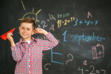 A schoolboy holding a red airplane in the hands of a training board