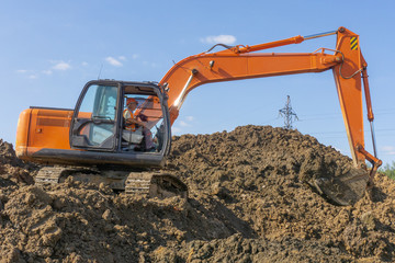 Orange excavator loads the land on a construction site..