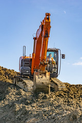Orange excavator loads the land on a construction site..