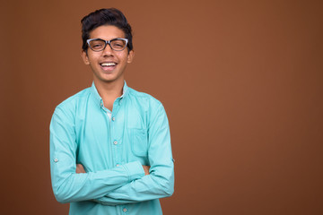 Young Indian boy wearing blue shirt looking smart against brown 