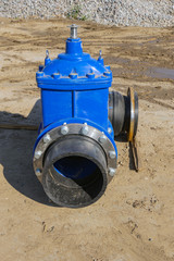 Elements of the pipeline, plastic pipes, cast iron valve at a construction site
