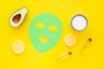 Skin care. Facial mask, cream and lotion near avocado and lemon on yellow background top view