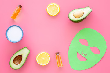 Skin care. Facial mask, cream and lotion near avocado and lemon on pink background top view copy space