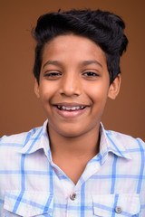 Young Indian boy wearing checkered shirt against brown backgroun