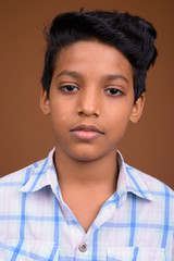 Young Indian boy wearing checkered shirt against brown backgroun