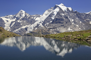 Summer in the Swiss Alps, Murren area, overlooking the Monch and Jungfrau mountains reflected in Grauseewli Lake, Canton of Bern, Switzerland, Europe