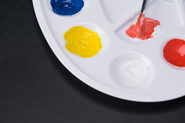 on a white palette set of gouache and brush, lie on a black background