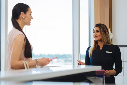 Friendly service. Joyful positive woman smiling to the client while standing at the reception