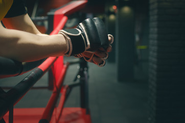 Boxing gloves on the fighter hands on the ropes of the boxing ring.