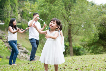 Naklejka na ściany i meble Asian family blowing soap bubbles outdoors