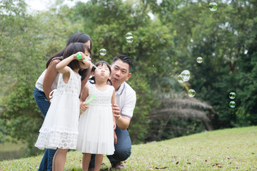 Obraz premium Family blowing soap bubbles at park