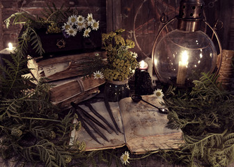 Old books, antique lamp, black candles and witch herbs. Mystic background with ritual esoteric...
