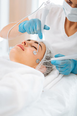 Professional facial therapy. Nice beautiful woman lying with her eyes close while having a microcurrent therapy session