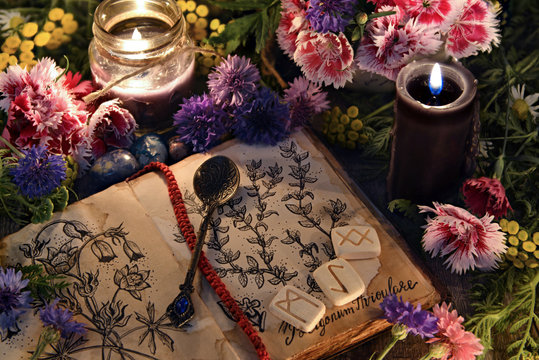 Still life with old book with botanical drawings, black candles, flowers and ritual objects. Mystic background with ritual esoteric objects, occult, fortune telling and halloween concept