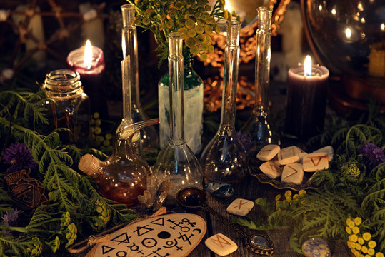 Alchemy still life with glass bottles and flask, runes, healing herbs and ritual objects. Mystic background with ritual esoteric objects, occult, fortune telling and halloween concept