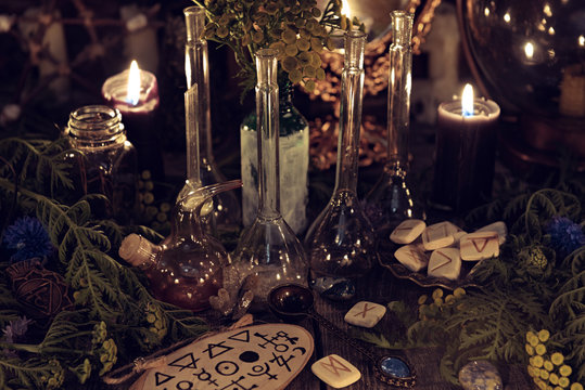 Still life with alchemy ritual objects, old bottles, herbs and black candles. Mystic background with ritual esoteric objects, occult, fortune telling and halloween concept
