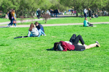 Fototapeta na wymiar People resting in the Park. Girls lie on the green grass