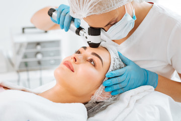 Professional dermatology. Pleasant young woman having her skin checked while visiting a dermatology clinic