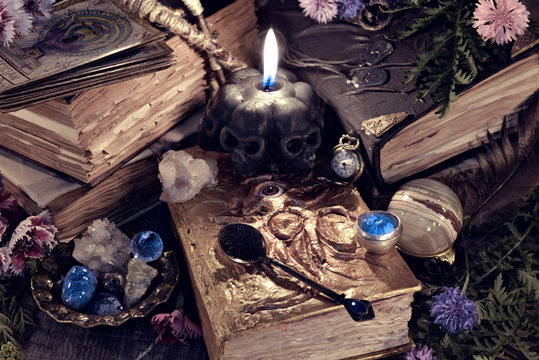 Still life with scary skull black candle, witch book and ritual objects in mystic light. Mystic background with ritual esoteric objects, occult, fortune telling and halloween concept