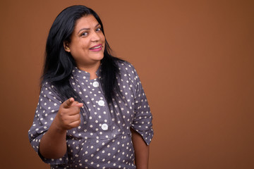 Portrait of mature Indian woman against brown background