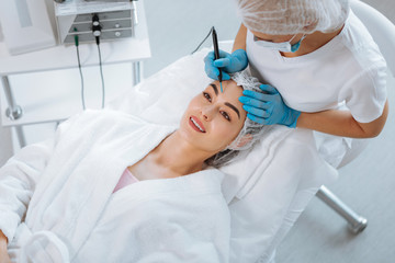 Fototapeta premium Aesthetic look. Delighted positive woman smiling while feeling happy about the cosmetology procedure