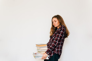 Unhappy teen girl student in college or university with stack of books white background
