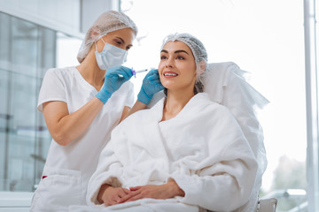 Beauty therapy. Delighted positive woman smiling while having a beauty injection