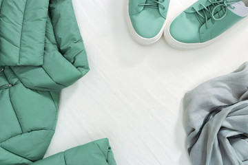 Spring flat lay from bright warm women jacket and shoes and scarf with copy space on white concrete background. Women's clothing set. Top view.