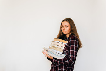 Unhappy teen girl student in college or university with stack of books white background