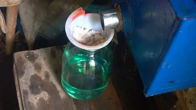 Pair is converted into a vodka, at the exit of the cooling system. The filtration moonshine and collection stage in a glass jar. Preparation a moonshine at home, distillation process.
