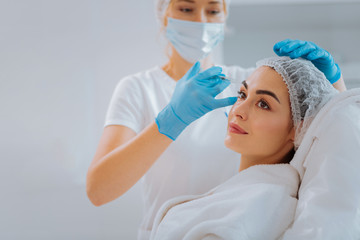 Naklejka premium Always young. Nice positive woman smiling while having anti age therapy