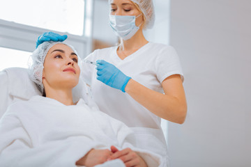 Important procedure. Serious nice beautician focusing on her work while doing an injection